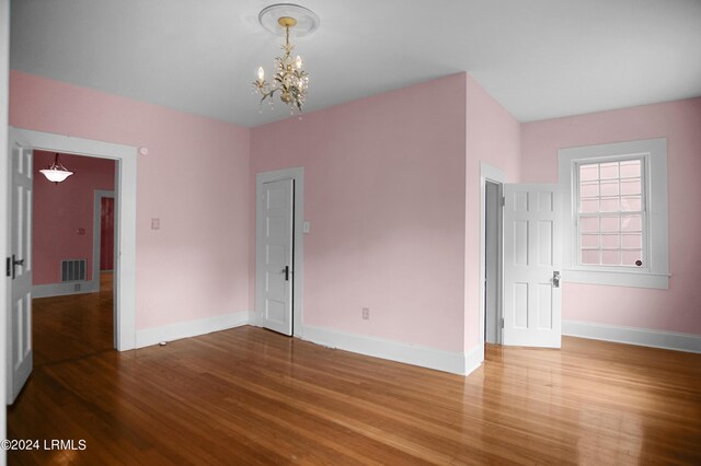 spare room featuring an inviting chandelier and wood-type flooring