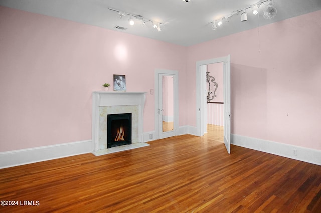 unfurnished living room featuring wood-type flooring and a high end fireplace