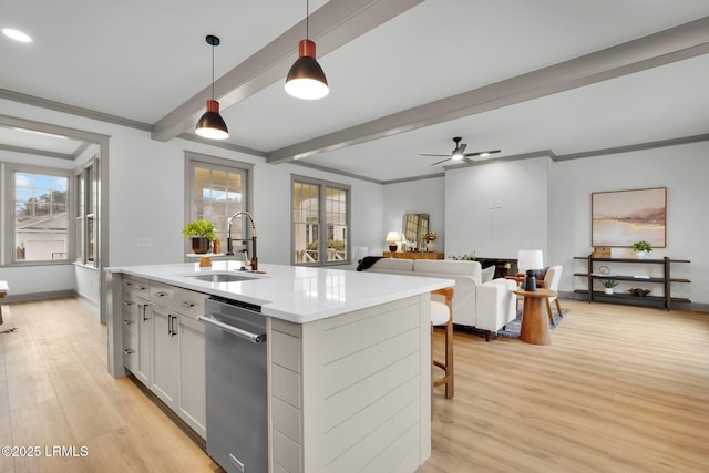 kitchen with pendant lighting, a center island with sink, light countertops, open floor plan, and white cabinets