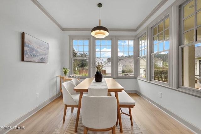 dining area with ornamental molding, light wood-type flooring, and baseboards