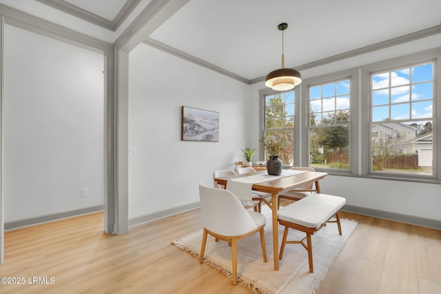 dining room featuring light wood-style floors, baseboards, and crown molding