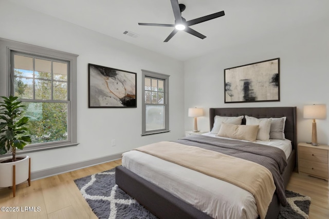 bedroom with light wood finished floors, ceiling fan, multiple windows, and visible vents