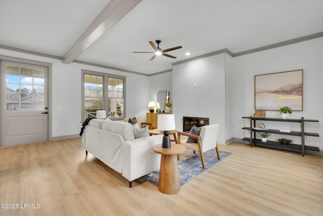 living room with baseboards, a tile fireplace, beamed ceiling, crown molding, and light wood-type flooring