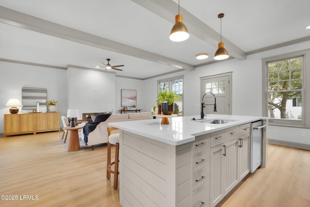 kitchen featuring a center island with sink, hanging light fixtures, open floor plan, white cabinets, and a sink