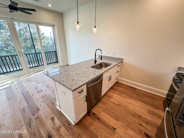 kitchen featuring pendant lighting, sink, dishwasher, light stone counters, and white cabinets