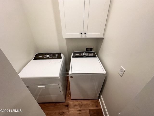 clothes washing area with independent washer and dryer, cabinets, and dark hardwood / wood-style floors