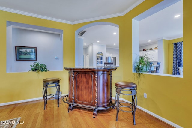 bar featuring ornamental molding and light wood-type flooring