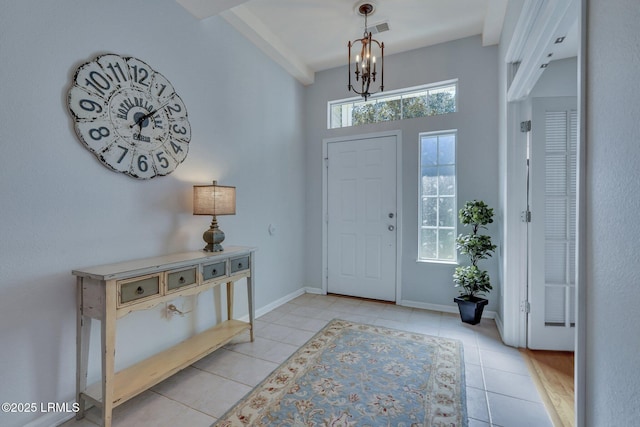 foyer entrance with light tile patterned flooring and an inviting chandelier