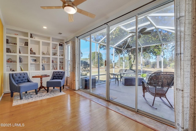 entryway with wood-type flooring, ceiling fan, and crown molding