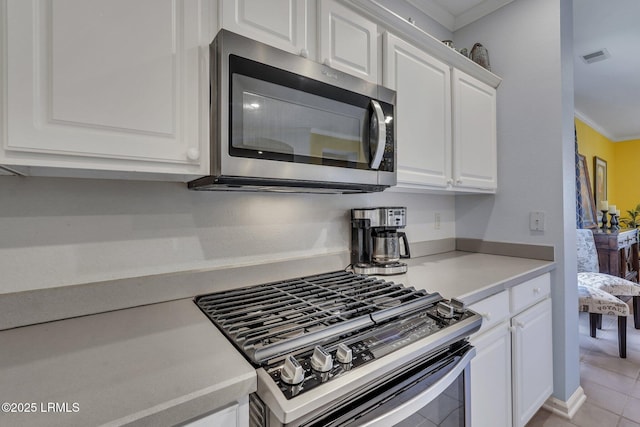 kitchen with crown molding, stainless steel appliances, light tile patterned floors, and white cabinets