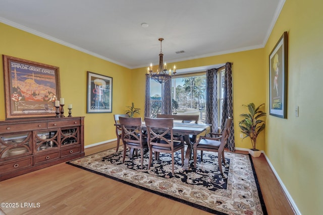 dining space with a notable chandelier, hardwood / wood-style flooring, and ornamental molding