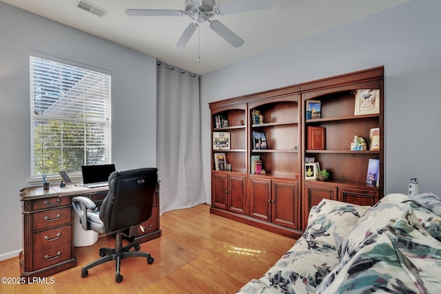 home office with light hardwood / wood-style flooring and ceiling fan