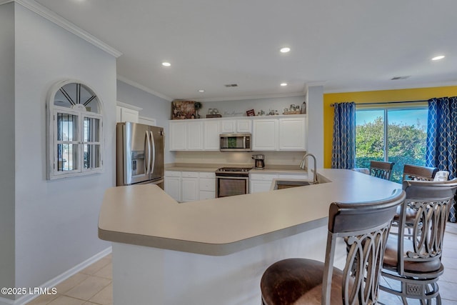 kitchen with sink, a breakfast bar area, white cabinetry, crown molding, and appliances with stainless steel finishes