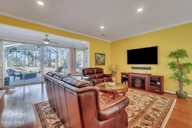 living room featuring hardwood / wood-style floors, ornamental molding, and ceiling fan