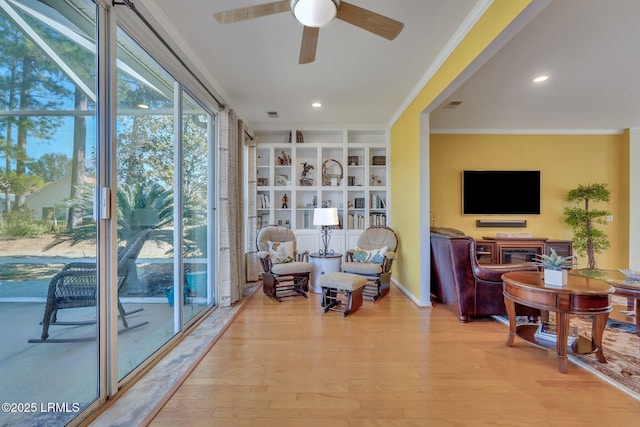 living area with crown molding, ceiling fan, light hardwood / wood-style floors, and built in features