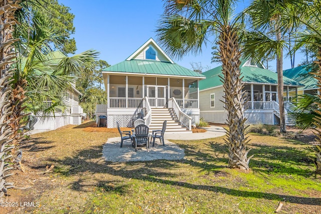 rear view of property featuring a patio, a sunroom, metal roof, and stairs