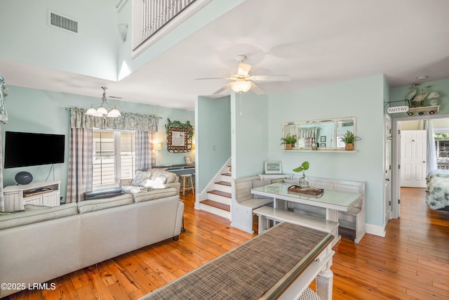 living room with baseboards, visible vents, ceiling fan with notable chandelier, and wood-type flooring