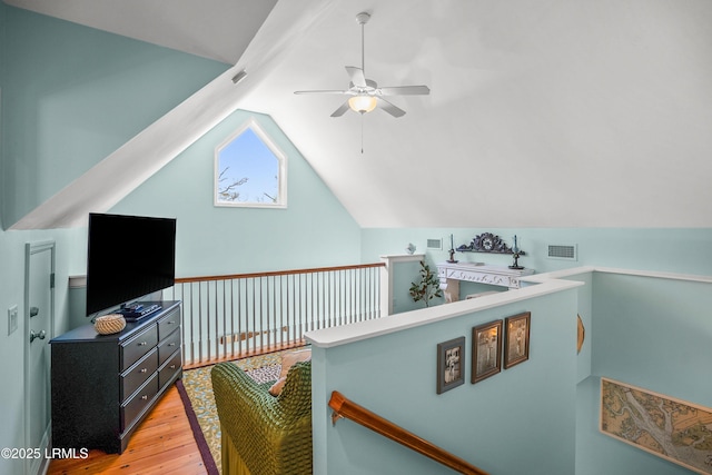 interior space featuring an upstairs landing, lofted ceiling, ceiling fan, and light wood-style flooring