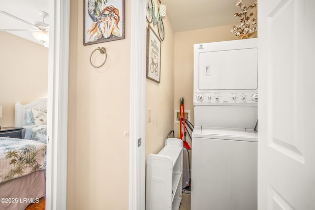 clothes washing area featuring stacked washer / dryer, laundry area, and a ceiling fan