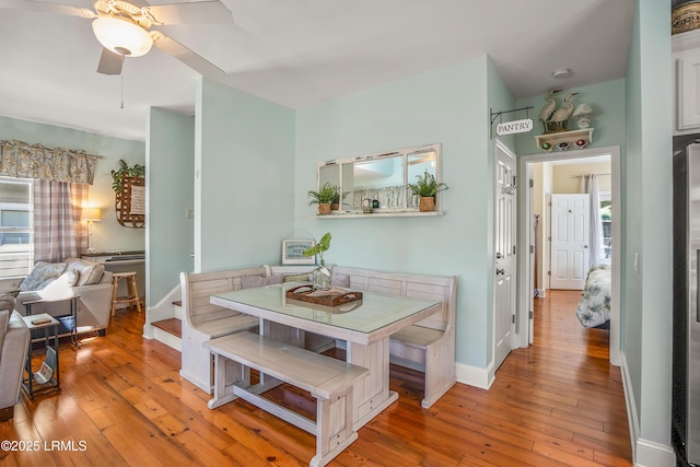 dining space featuring baseboards, light wood-style floors, ceiling fan, and breakfast area