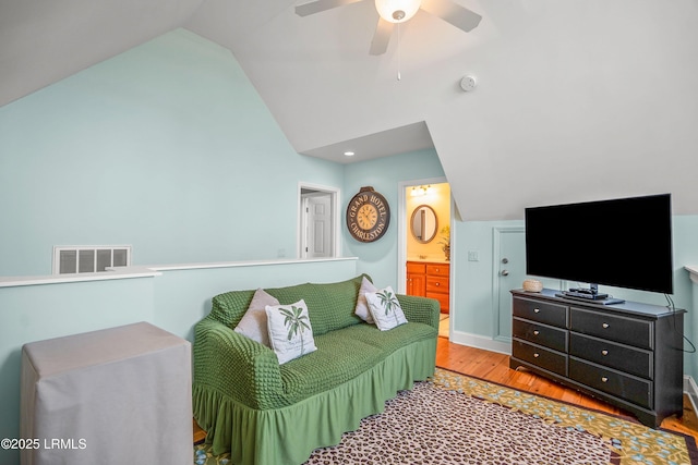 living area with vaulted ceiling, baseboards, visible vents, a ceiling fan, and wood finished floors