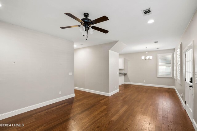 unfurnished living room featuring dark wood-type flooring and ceiling fan with notable chandelier