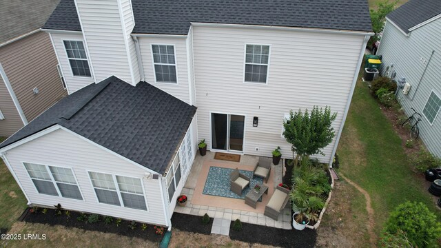 back of house featuring a lawn, a shingled roof, and a patio
