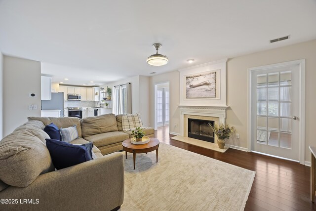 living area featuring visible vents, baseboards, recessed lighting, dark wood finished floors, and a fireplace