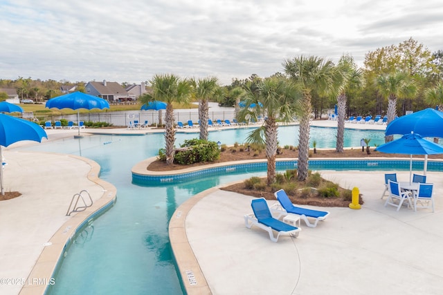 pool featuring fence, a water slide, and a patio
