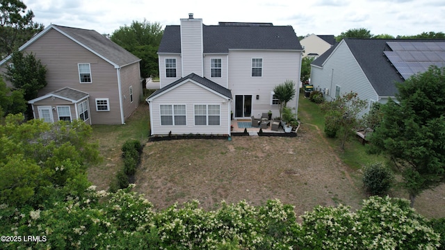rear view of property featuring a chimney, a patio area, and a yard