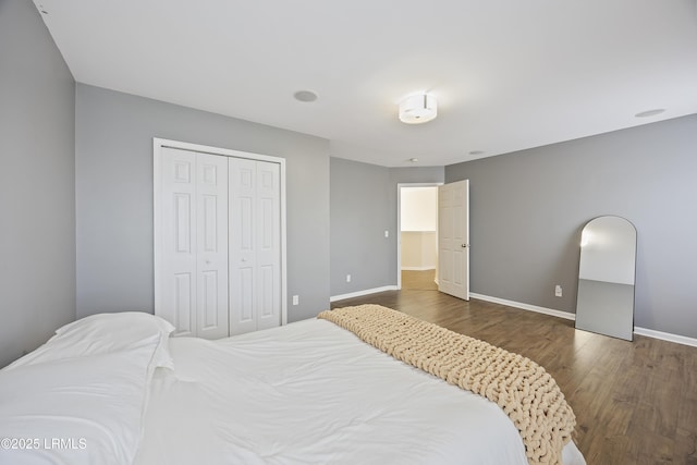 bedroom with baseboards, wood finished floors, and a closet