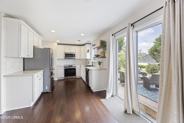 kitchen with dark wood-style floors, a sink, decorative backsplash, light countertops, and appliances with stainless steel finishes