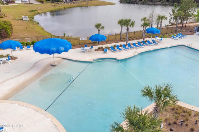pool with fence, a patio area, and a water view