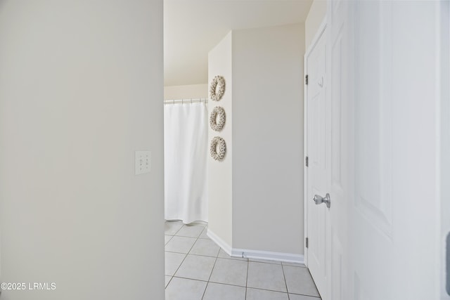 hallway with light tile patterned floors and baseboards