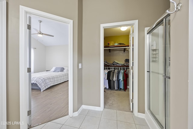 bathroom with baseboards, a shower stall, ceiling fan, and a spacious closet