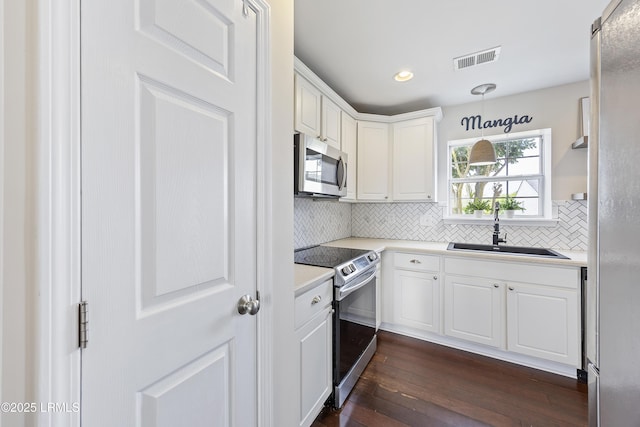 kitchen featuring stainless steel appliances, light countertops, a sink, white cabinetry, and visible vents