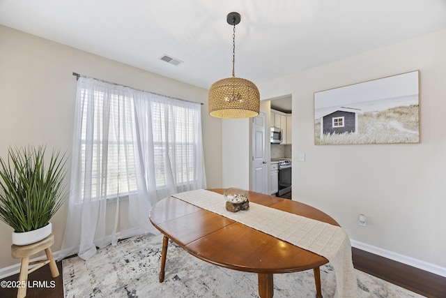 dining area with visible vents, light wood-style flooring, and baseboards