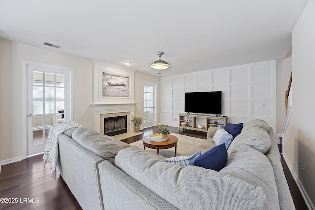 living area with a fireplace, visible vents, baseboards, and dark wood-type flooring