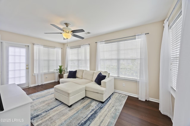 living area featuring baseboards, visible vents, wood finished floors, and ceiling fan