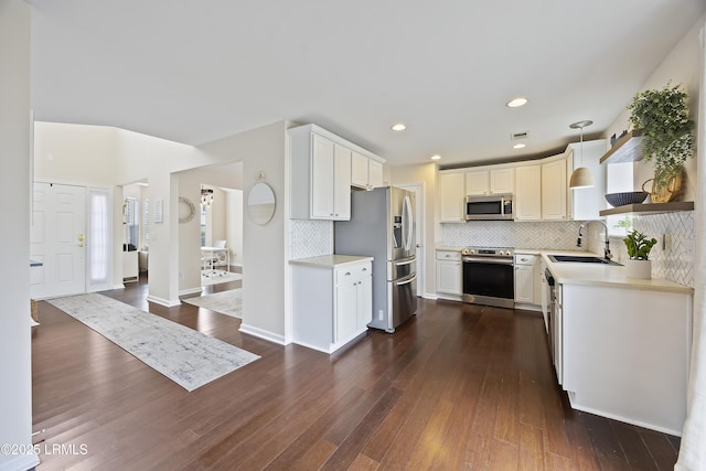kitchen featuring appliances with stainless steel finishes, decorative backsplash, light countertops, and a sink
