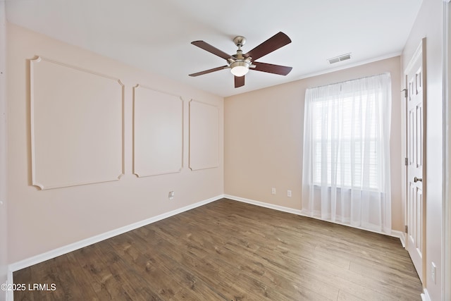 unfurnished room featuring baseboards, visible vents, wood finished floors, and a ceiling fan