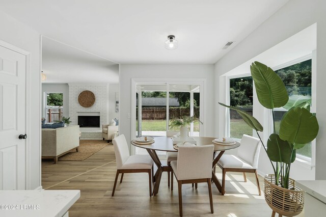 dining room featuring a brick fireplace and hardwood / wood-style flooring