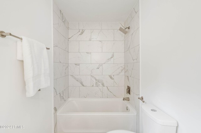 bathroom with toilet and tiled shower / bath