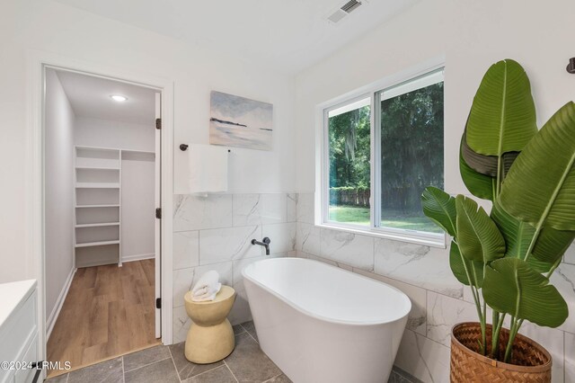 bathroom with plenty of natural light, tile walls, and a washtub