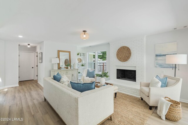 living room with a brick fireplace and light hardwood / wood-style flooring