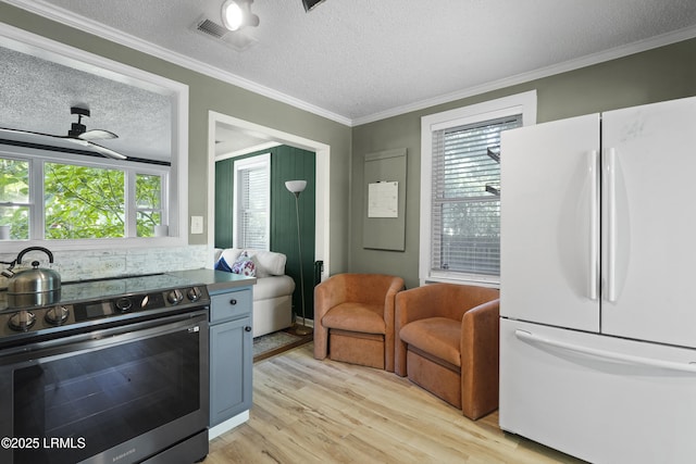 174 James St, Beaufort, SC 29902 - kitchen with freestanding refrigerator, stainless steel range with electric cooktop, a textured ceiling, light wood-style floors, and crown molding