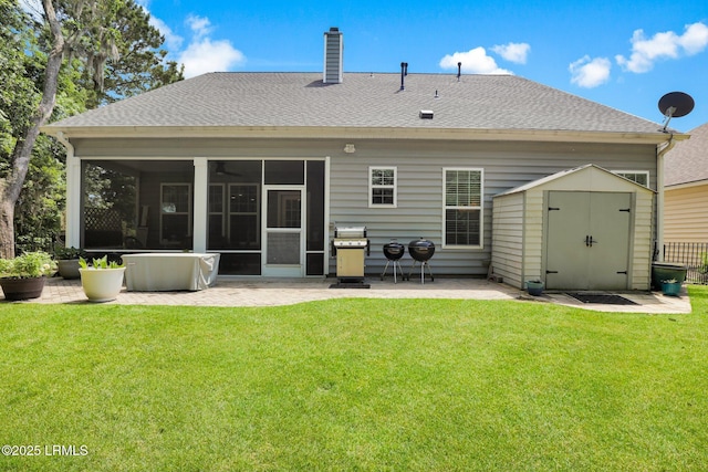 rear view of house featuring roof with shingles, a patio, a sunroom, and a shed