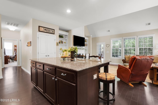 kitchen featuring baseboards, visible vents, a breakfast bar area, and open floor plan
