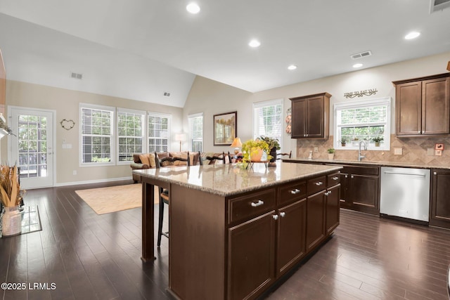 kitchen with dishwasher, a kitchen breakfast bar, open floor plan, lofted ceiling, and visible vents