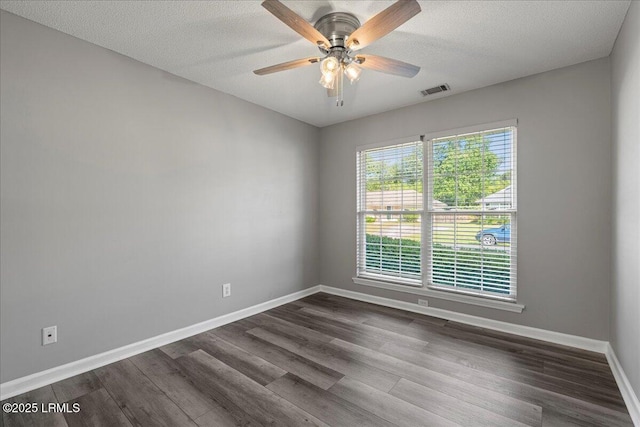 spare room featuring baseboards, dark wood-style floors, a ceiling fan, and a textured ceiling